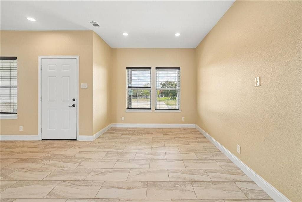 9060 Mitchell Bend Court, Granbury, TX 76048 Neutral-toned interior space featuring light-colored stone-finish floor tile, recessed ceiling lighting, and dual windows