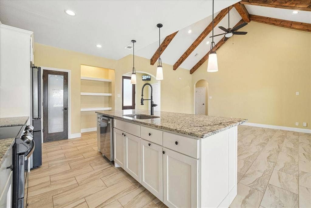 9060 Mitchell Bend Court, Granbury, TX 76048 Vaulted ceiling with exposed wood beams, kitchen island with stone countertop, tile flooring, pendant lighting, and built-in shelving