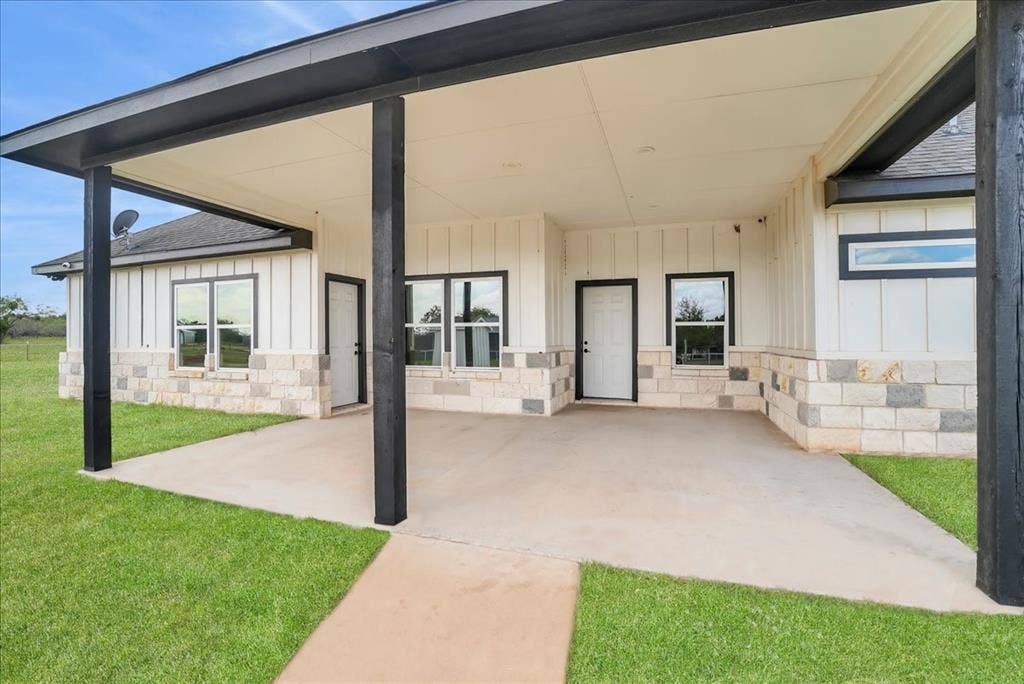 9060 Mitchell Bend Court, Granbury, TX 76048 Covered patio featuring black structural support beams, vertical siding, and a stone facade foundation