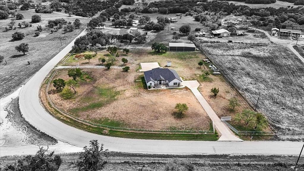9060 Mitchell Bend Court, Granbury, TX 76048 Corner lot featuring a multi-gabled roof, expansive acreage, paved driveway, and detached storage structure