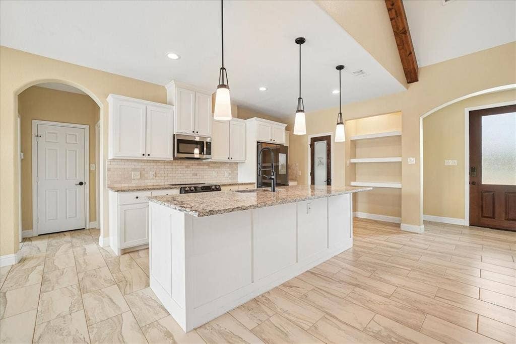 9060 Mitchell Bend Court, Granbury, TX 76048 Kitchen featuring white cabinetry, an expansive central island with stone-finish countertops, tile backsplash, pendant lighting, and wood-finish flooring