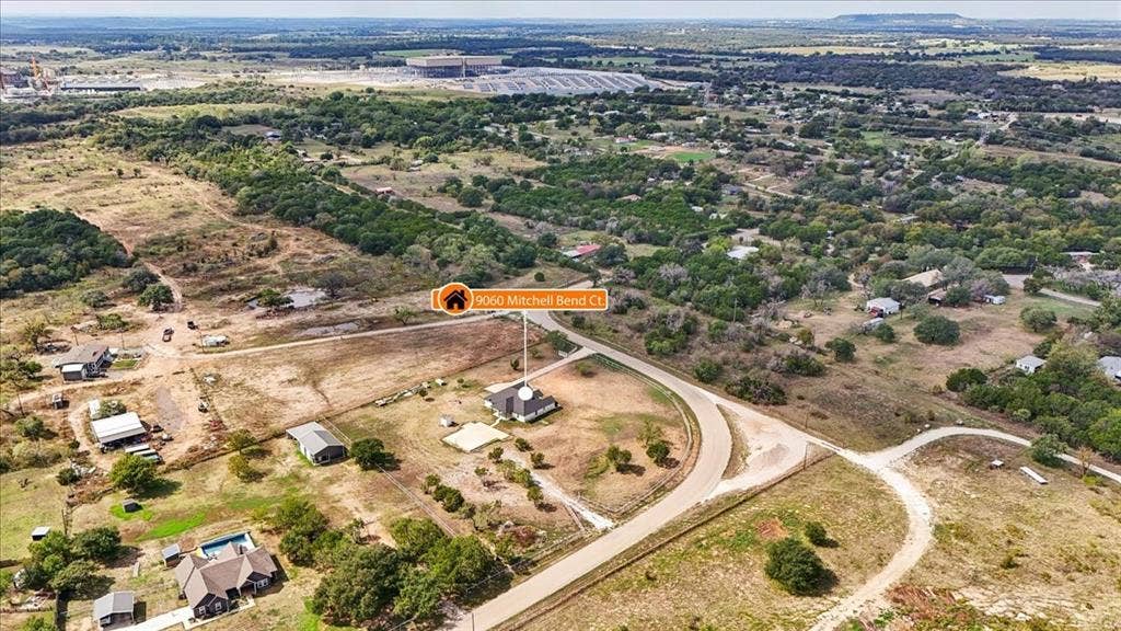 9060 Mitchell Bend Court, Granbury, TX 76048 Aerial view of a sprawling property featuring a paved driveway, detached secondary structure, and extensive open acreage