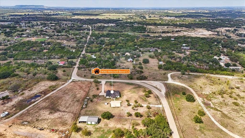 9060 Mitchell Bend Court, Granbury, TX 76048 Aerial perspective of a sprawling acreage lot featuring a residential structure, detached workshop, paved driveway, and established native vegetation