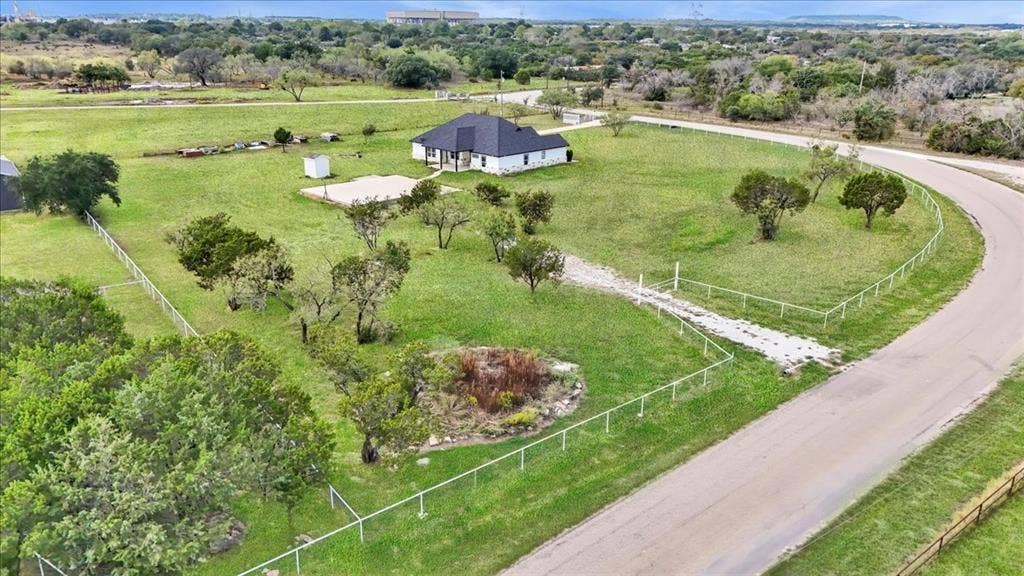 9060 Mitchell Bend Court, Granbury, TX 76048 Expansive lot featuring mature trees, a perimeter wire fence, a dedicated gravel driveway, and a detached outbuilding