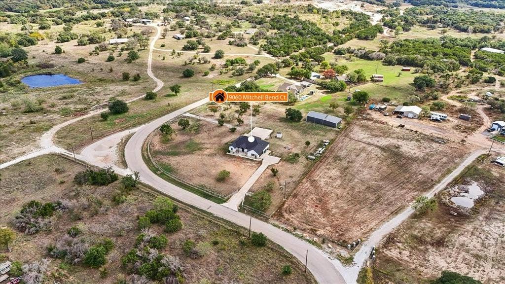 9060 Mitchell Bend Court, Granbury, TX 76048 Aerial perspective of a detached residence featuring a paved driveway, expansive acreage, and native landscape
