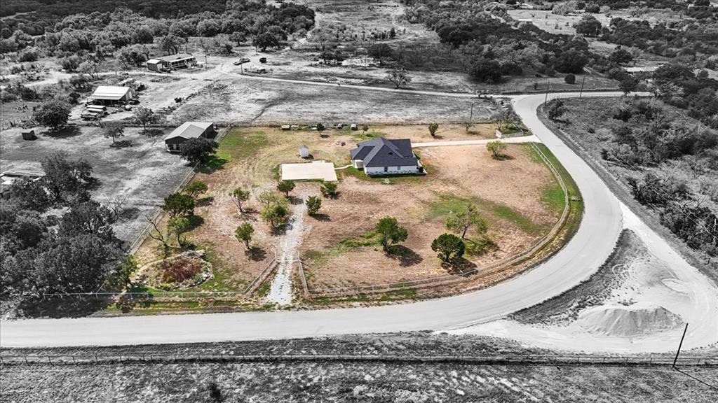 9060 Mitchell Bend Court, Granbury, TX 76048 Expansive acreage featuring a paved road frontage, mature trees, a concrete parking pad, and a fenced perimeter