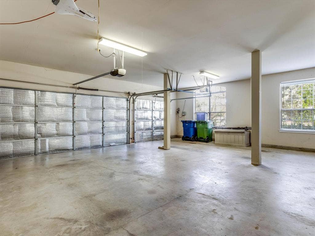 Multi-vehicle garage featuring insulated garage doors, concrete flooring, structural support columns, and dual-pane windows