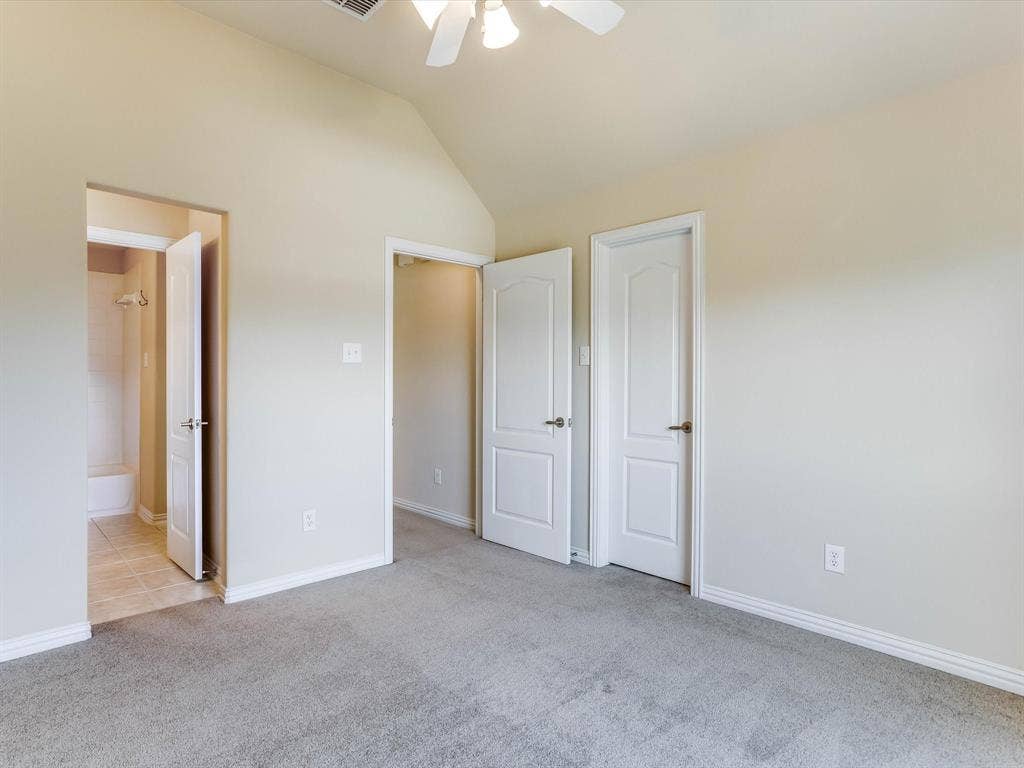 Vaulted ceiling featuring a central light fixture, neutral carpeted flooring, and white two-panel interior doors