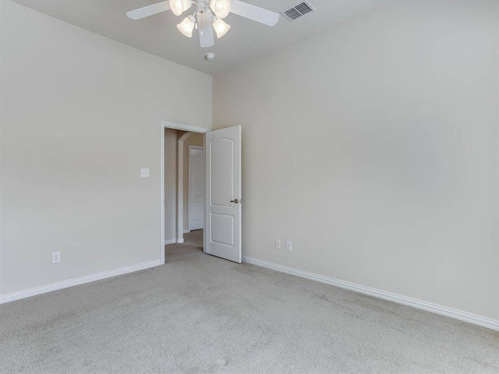 Neutral wall tones paired with neutral carpeting, high ceilings, and an overhead ceiling fan with integrated lighting