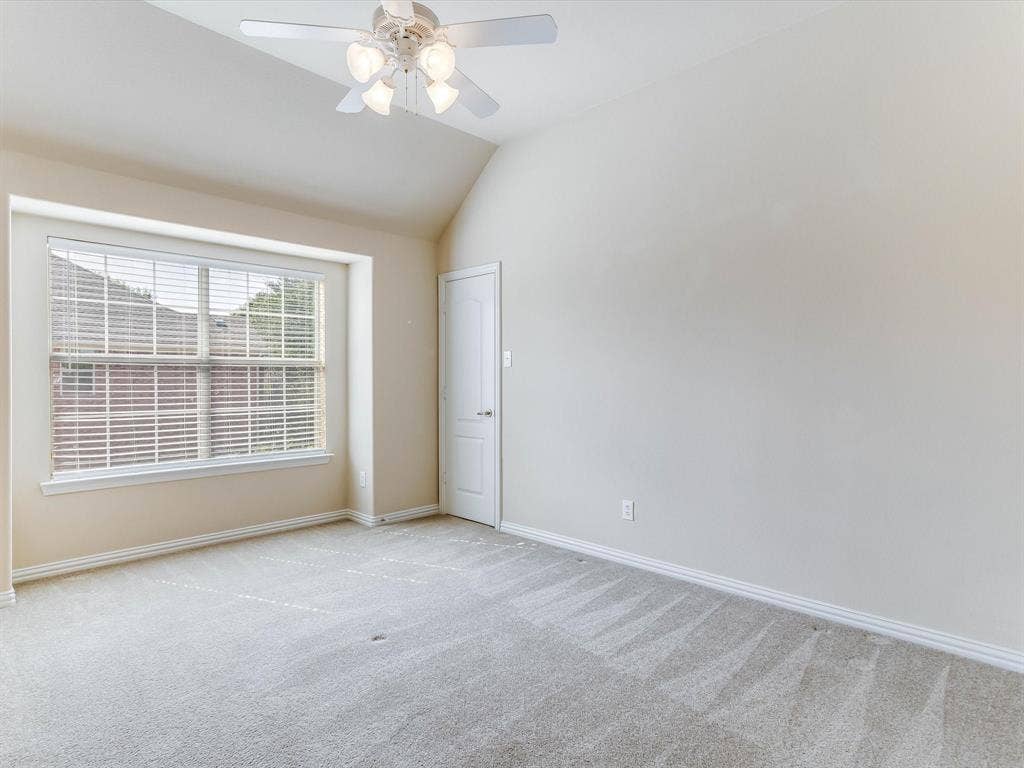 Vaulted ceiling with an attached multi-light ceiling fan, neutral wall tones, window with interior blinds, and wall-to-wall carpeting