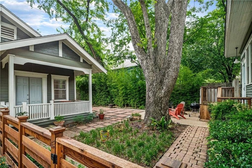5936 Bryan Parkway, #B, Dallas, TX 75206 Covered front porch with white railing, brick-paved patio, mature shade tree, and wood-slat privacy fencing