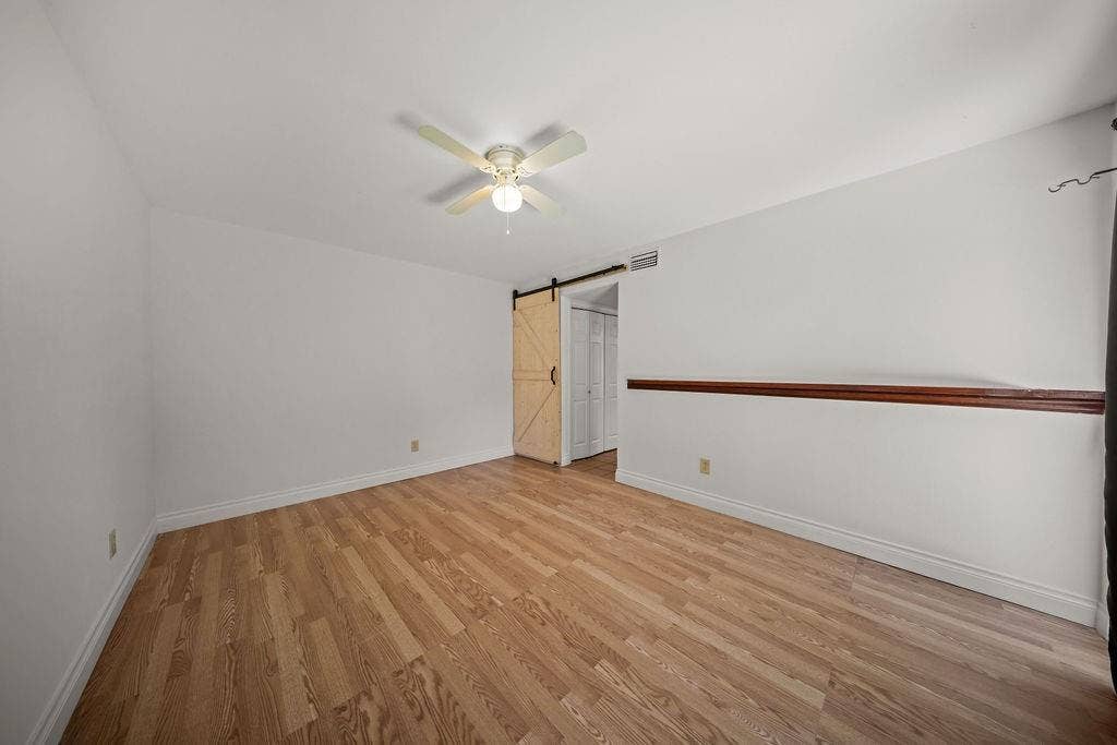 738 Intrepid Drive, Garland, TX 75043 Room interior featuring wood-finish flooring, a light-toned sliding barn door, and a wooden chair rail accent