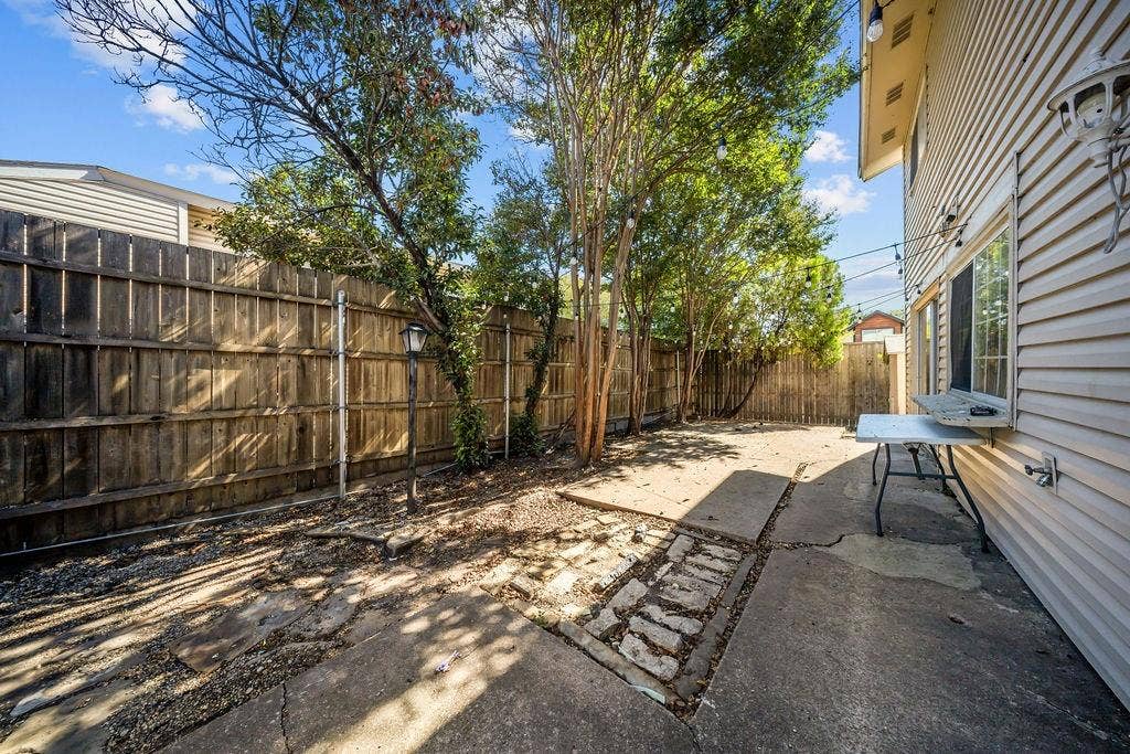 738 Intrepid Drive, Garland, TX 75043 Backyard featuring a wood privacy fence, concrete patio area, mature trees, and vinyl siding exterior