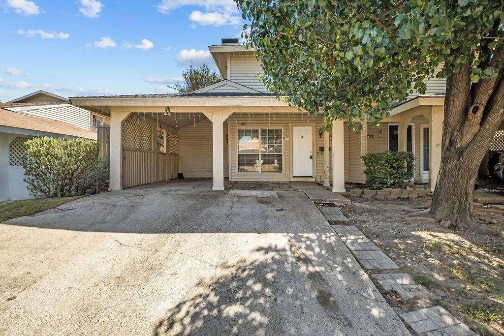 738 Intrepid Drive, Garland, TX 75043 Two-story exterior featuring light-colored horizontal siding, an attached carport with decorative lattice privacy screening, and a concrete driveway
