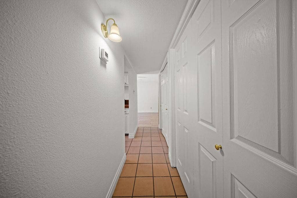 738 Intrepid Drive, Garland, TX 75043 Ceramic tile flooring, white bi-fold closet doors, wall-mounted light fixture with frosted glass shade, and textured wall finish
