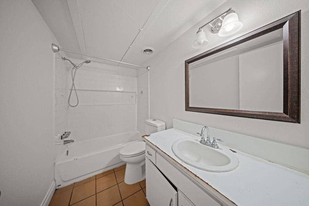 738 Intrepid Drive, Garland, TX 75043 Bathroom featuring a vanity with an integrated basin, a combination tub and shower with a handheld sprayer, tiled flooring, and a wall-mounted light fixture above the vanity mirror