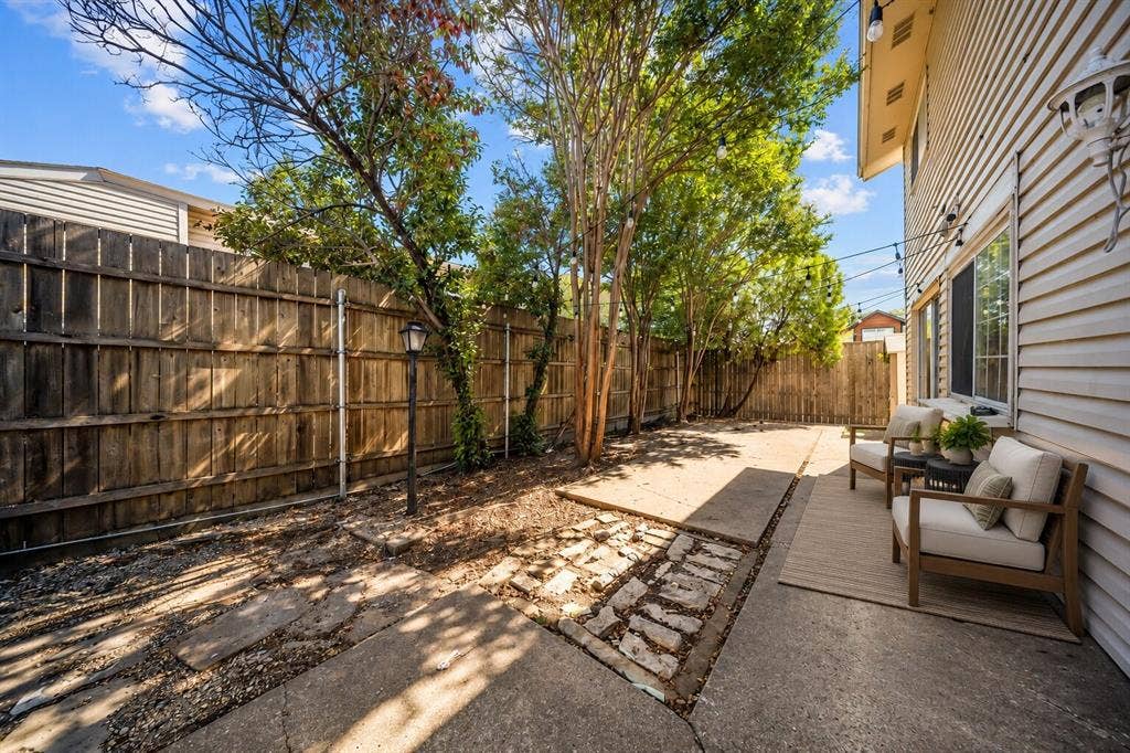 738 Intrepid Drive, Garland, TX 75043 Concrete patio, wood-slat privacy fencing, established mature trees, and overhead string lighting