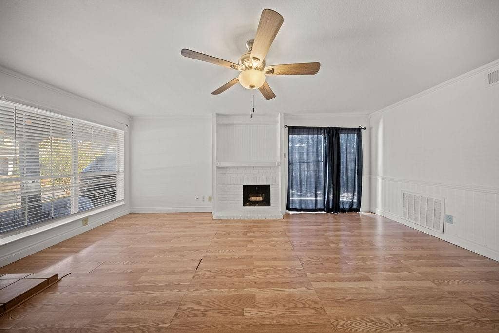 738 Intrepid Drive, Garland, TX 75043 Interior space featuring wood-finish flooring, a painted brick fireplace with built-in shelving, a ceiling fan with integrated lighting, and horizontal window blinds