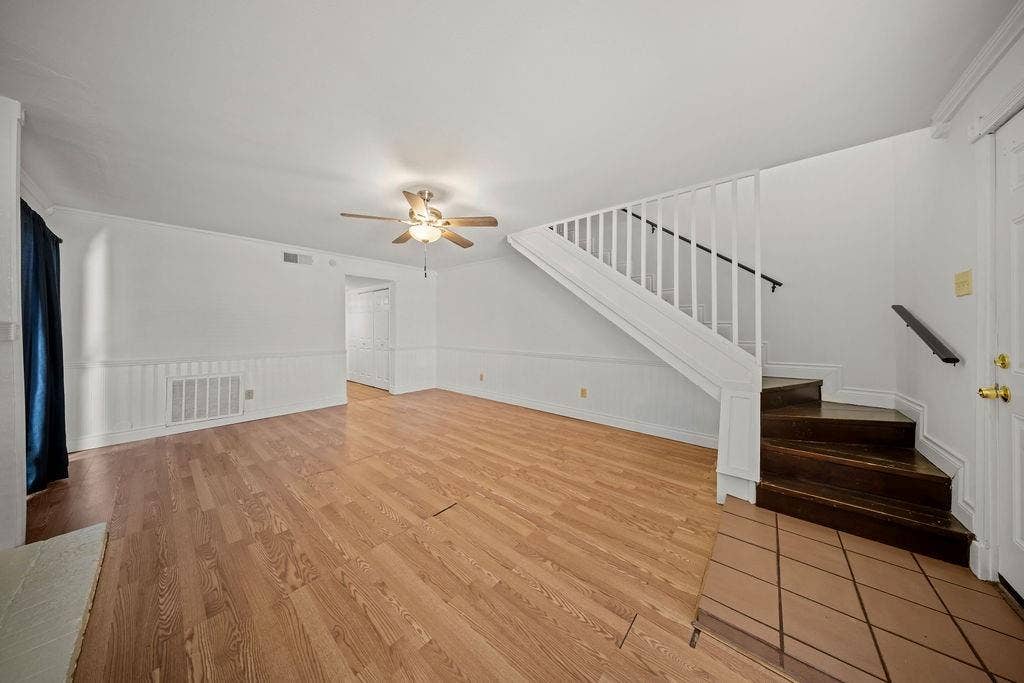 738 Intrepid Drive, Garland, TX 75043 Open living area featuring wood-finish flooring, wainscoting, staircase with white railing, and ceiling fan