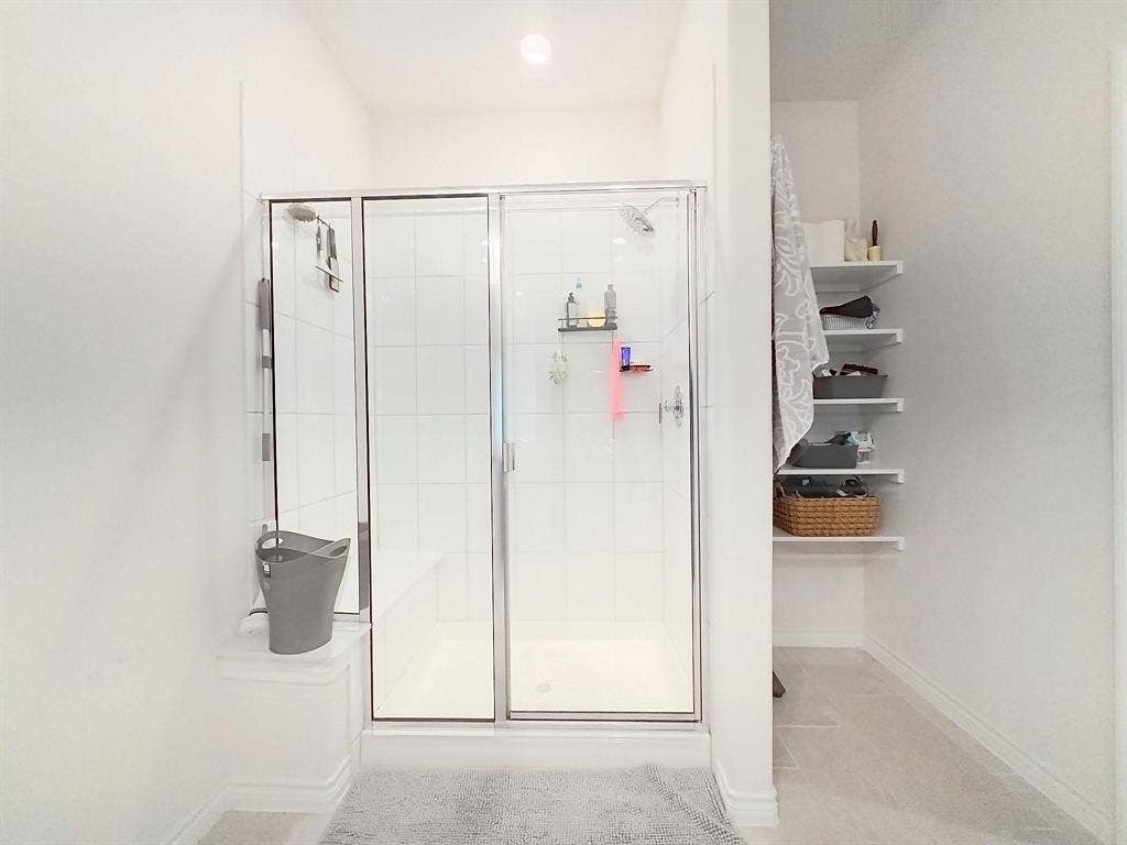 7400 Seton Place, McKinney, TX 75071 Walk-in shower featuring white wall tile, a built-in bench, a glass enclosure, and built-in wall shelving