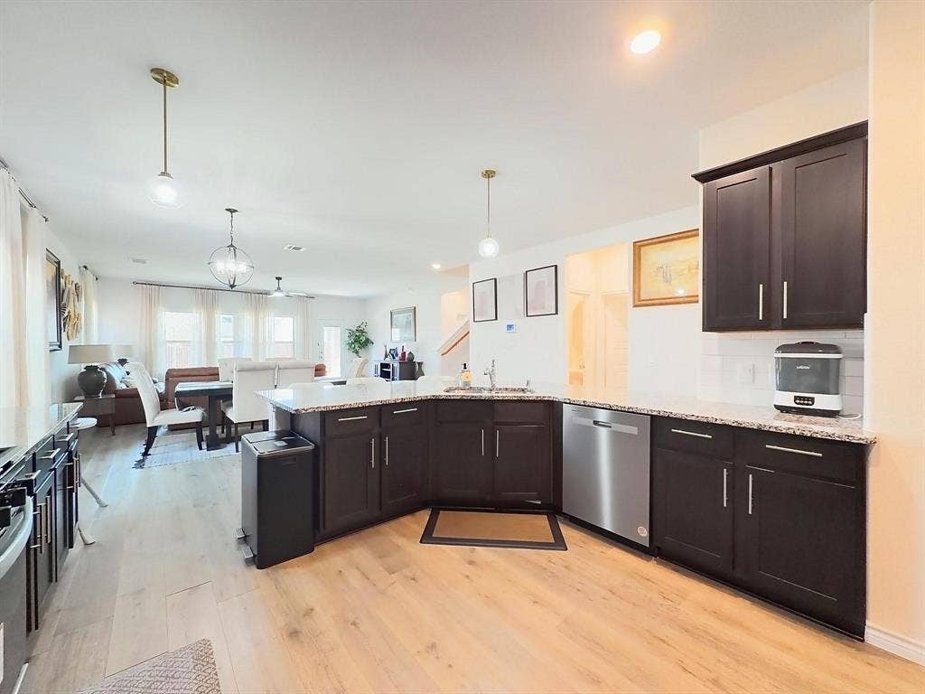 7400 Seton Place, McKinney, TX 75071 Kitchen featuring dark-finish cabinetry, stone-surface countertops, stainless steel dishwasher, wood-finish flooring, and pendant lighting