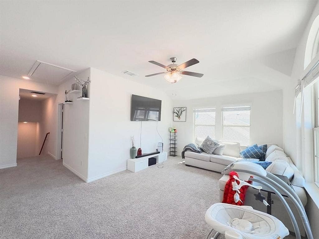 7400 Seton Place, McKinney, TX 75071 Living area featuring a vaulted ceiling, neutral wall-to-wall carpeting, a multi-blade ceiling fan with integrated lighting, and large windows