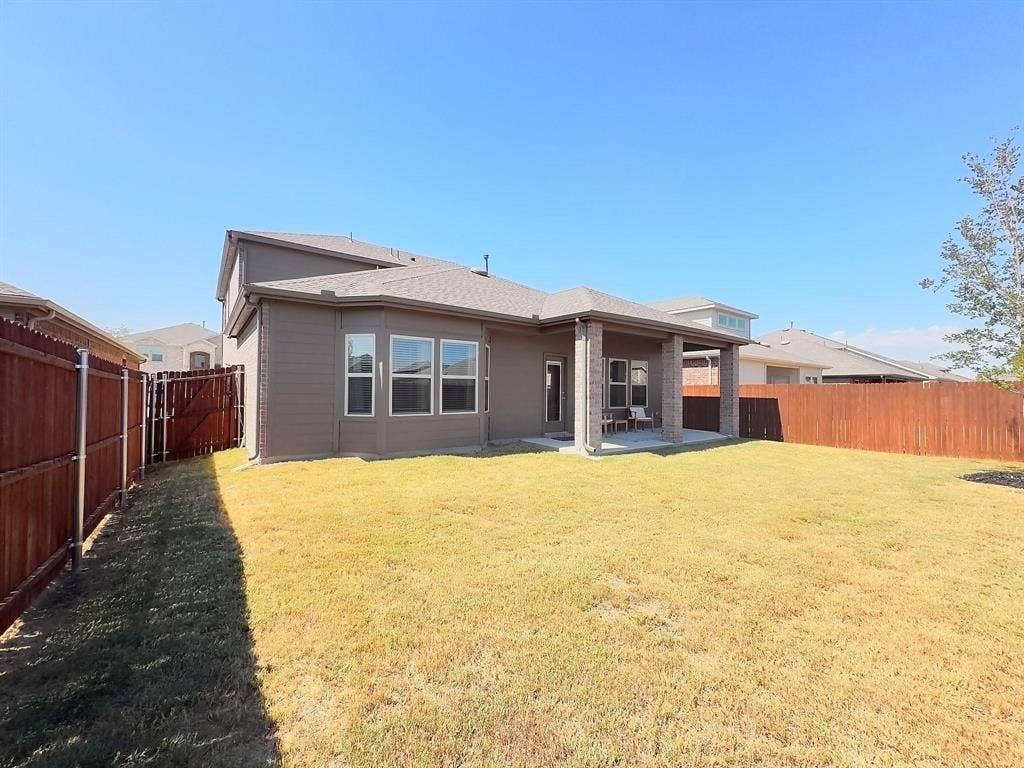 7400 Seton Place, McKinney, TX 75071 Rear exterior featuring a covered patio with masonry columns, a sprawling lawn, and a tall wood privacy fence