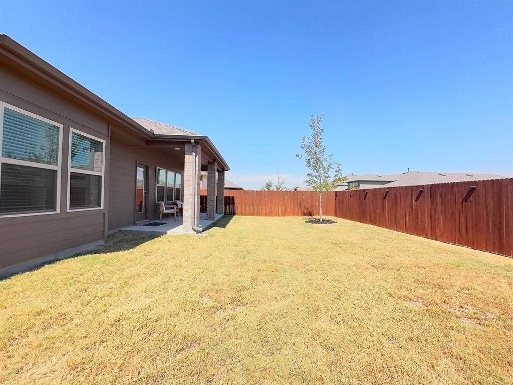 7400 Seton Place, McKinney, TX 75071 Rear exterior featuring a covered concrete patio, horizontal siding, vertical support pillars, and a wood privacy fence enclosing the backyard