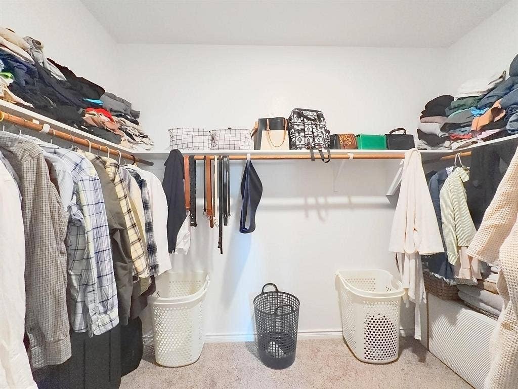 7400 Seton Place, McKinney, TX 75071 Walk-in closet featuring U-shaped configuration, wall-to-wall carpeting, and integrated wood-finish shelving and hanging rods
