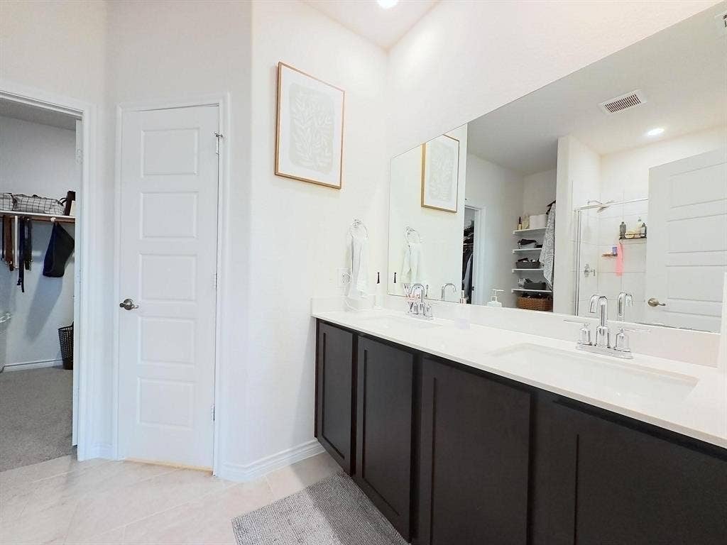 7400 Seton Place, McKinney, TX 75071 Dual-sink vanity with dark cabinetry and stone countertop, large-format mirror, and tile flooring