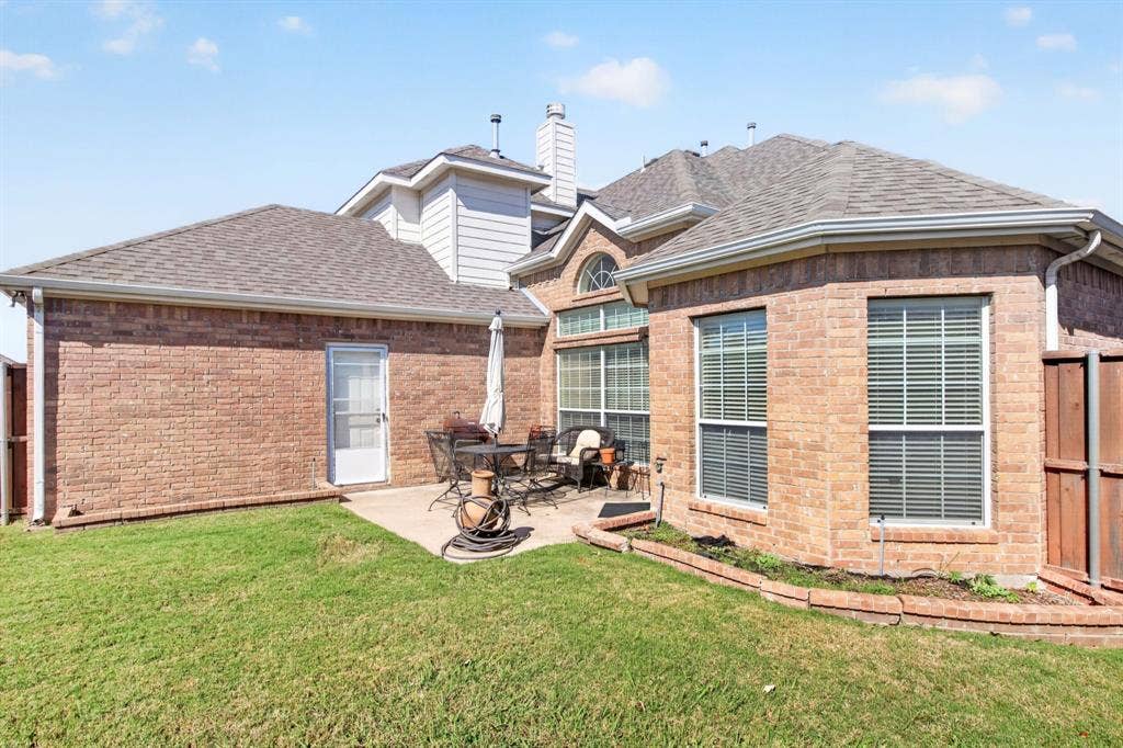 10657 Coach House Lane, Frisco, TX 75035 Rear exterior view showing the brick facade, patio and lawn.
