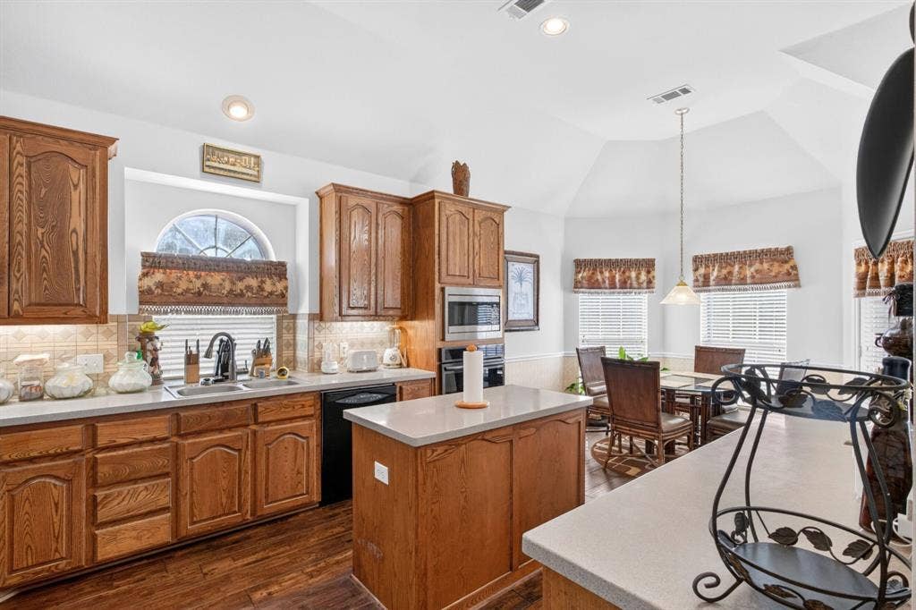 10657 Coach House Lane, Frisco, TX 75035 Island kitchen with gas cooking, abundant wood cabinetry, built-in ovens and an adjoining breakfast area.