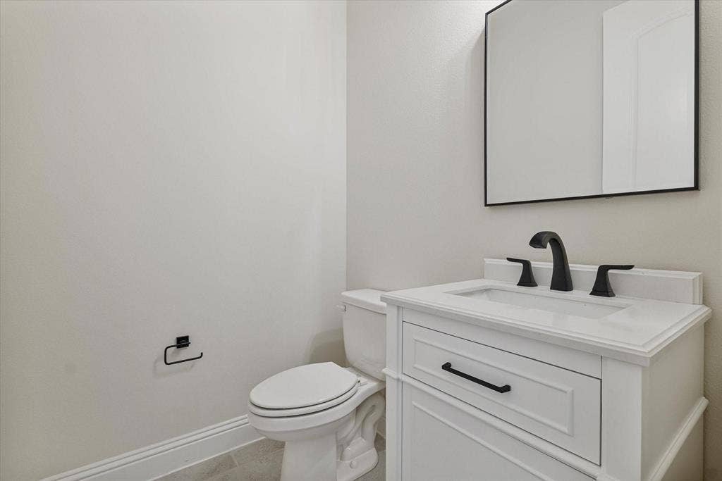 2817 Yarmouth Street, Celina, TX 75009 White vanity with a rectangular sink, matte black faucet, and matching cabinet hardware, complemented by a square mirror with a black frame