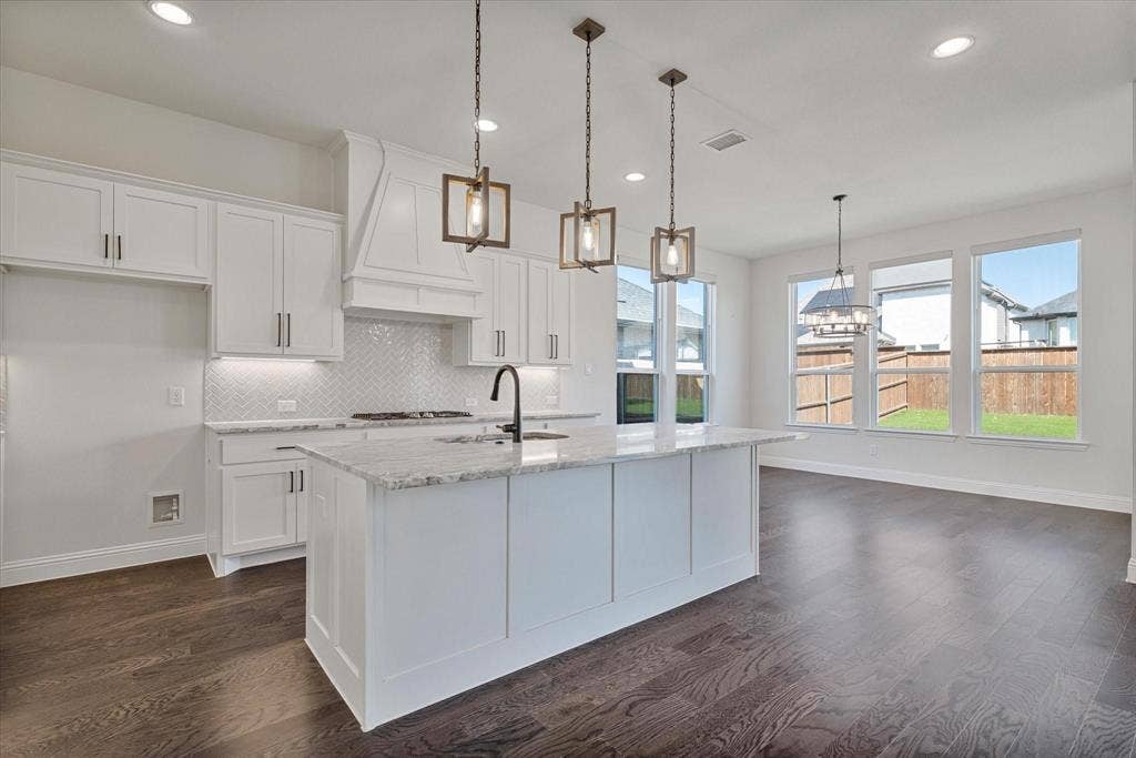 2817 Yarmouth Street, Celina, TX 75009 Kitchen featuring white cabinetry, quartz countertops, herringbone pattern tile backsplash, a center island with a matte black faucet, and wood-finish flooring