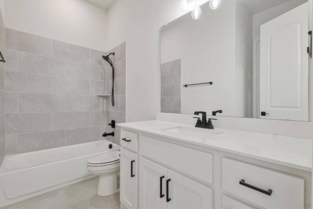 2817 Yarmouth Street, Celina, TX 75009 White vanity featuring a solid surface countertop, undermount sink, and matte black hardware, paired with a bathtub surround in grey rectangular tile and matte black plumbing fixtures