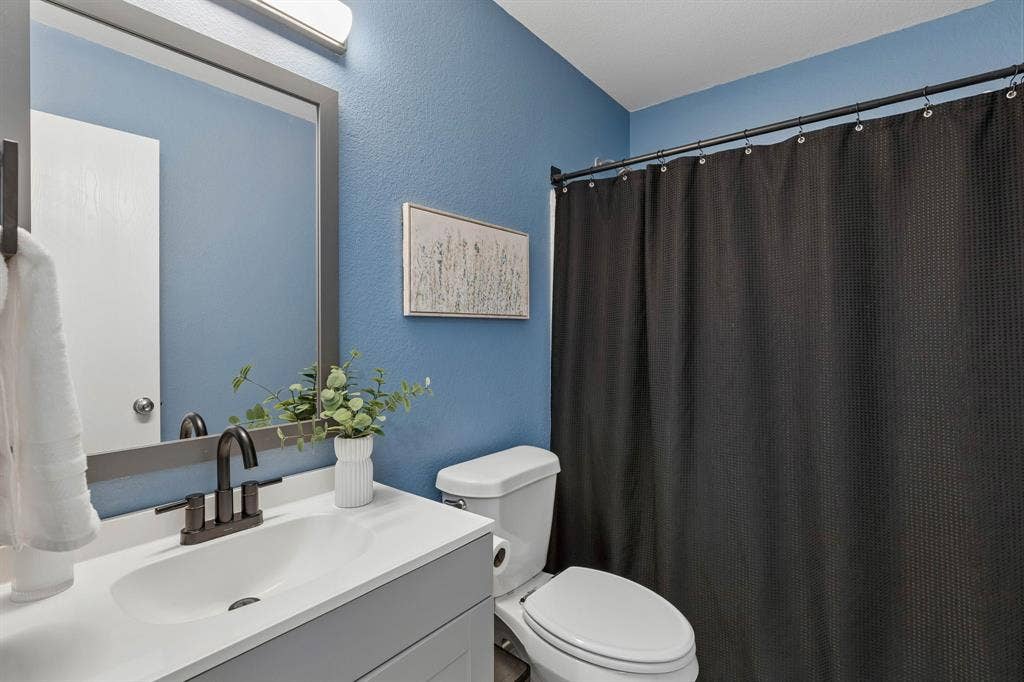 The secondary bathroom features an updated vanity, a framed mirror, black hardware, and a tub in shower.