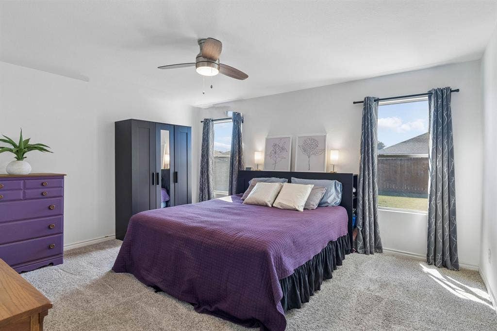 Welcome to the primary suite! Featuring an updated ceiling fan, carpet, two large windows with views to the large backyard.