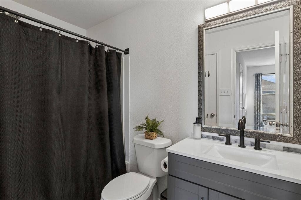 The primary bathroom features a garden tub and shower, an updated vanity with a decorative framed mirror, and convenient access to the walk-in closet.