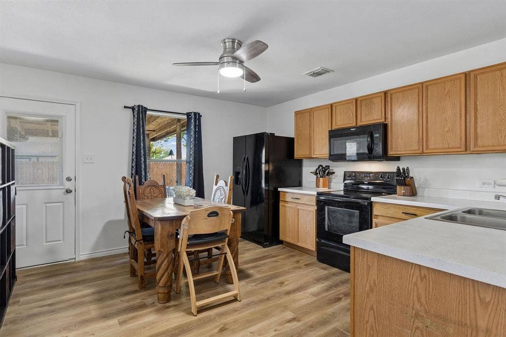 The eat-in kitchen features ample cabinet and counter space, LVP flooring, an updated ceiling fan, and black appliances. With access to the back patio and yard.