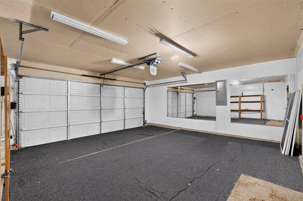 3107 Westview Drive, McKinney, TX 75070 Multi-car garage featuring a sectional overhead door, wall-to-wall mirrored panels, fluorescent overhead lighting, and carpeted flooring