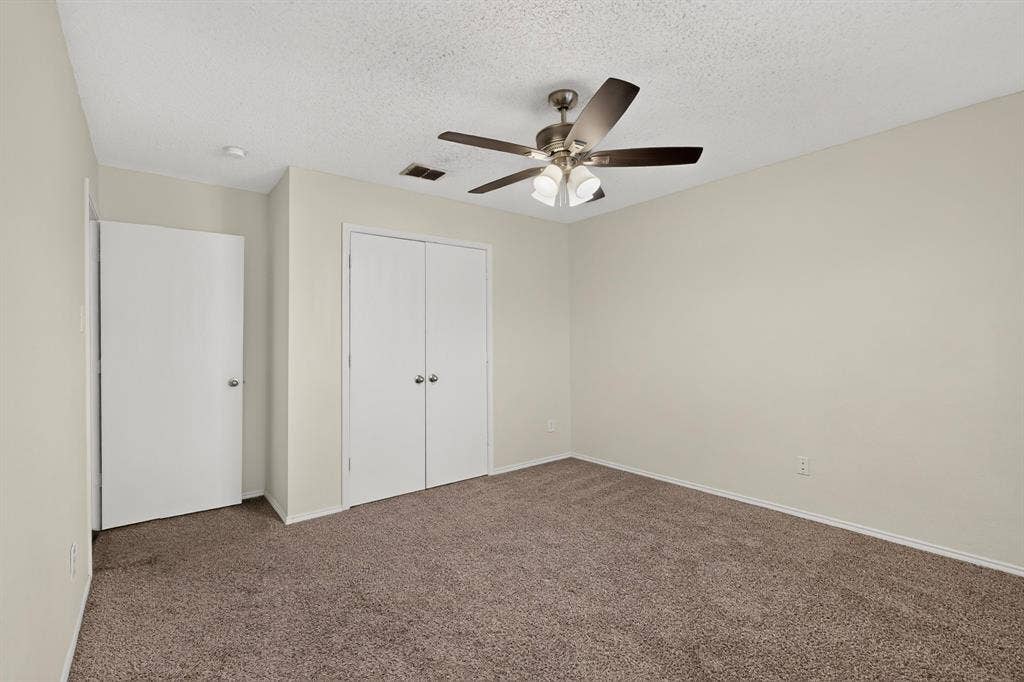 3107 Westview Drive, McKinney, TX 75070 Neutral-toned interior featuring wall-to-wall carpeting, dual-door reach-in closet, and a multi-blade ceiling fan with integrated lighting