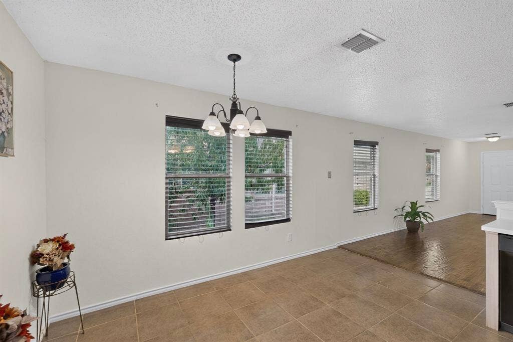 3107 Westview Drive, McKinney, TX 75070 Open concept interior featuring ceramic tile flooring, wood-finish flooring, multi-pane windows with horizontal blinds, and a five-light chandelier