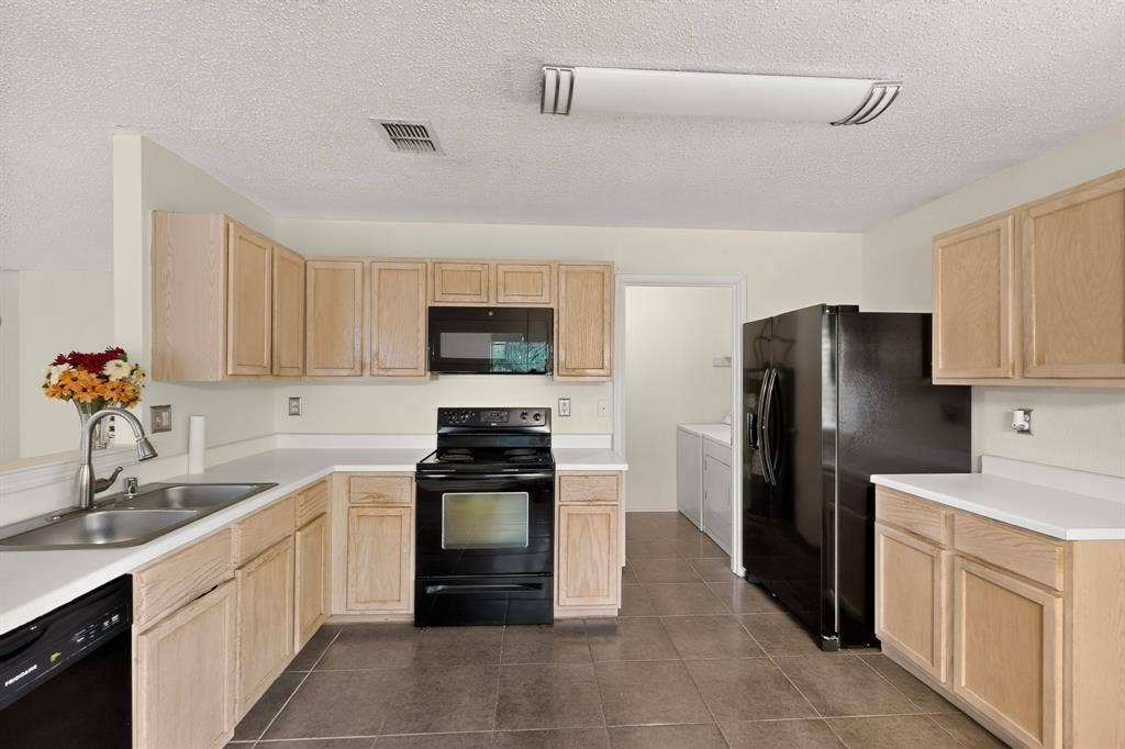 3107 Westview Drive, McKinney, TX 75070 Kitchen featuring light-finish cabinetry, white countertops, large-format tile flooring, a black suite of appliances, and a stainless steel dual-basin sink