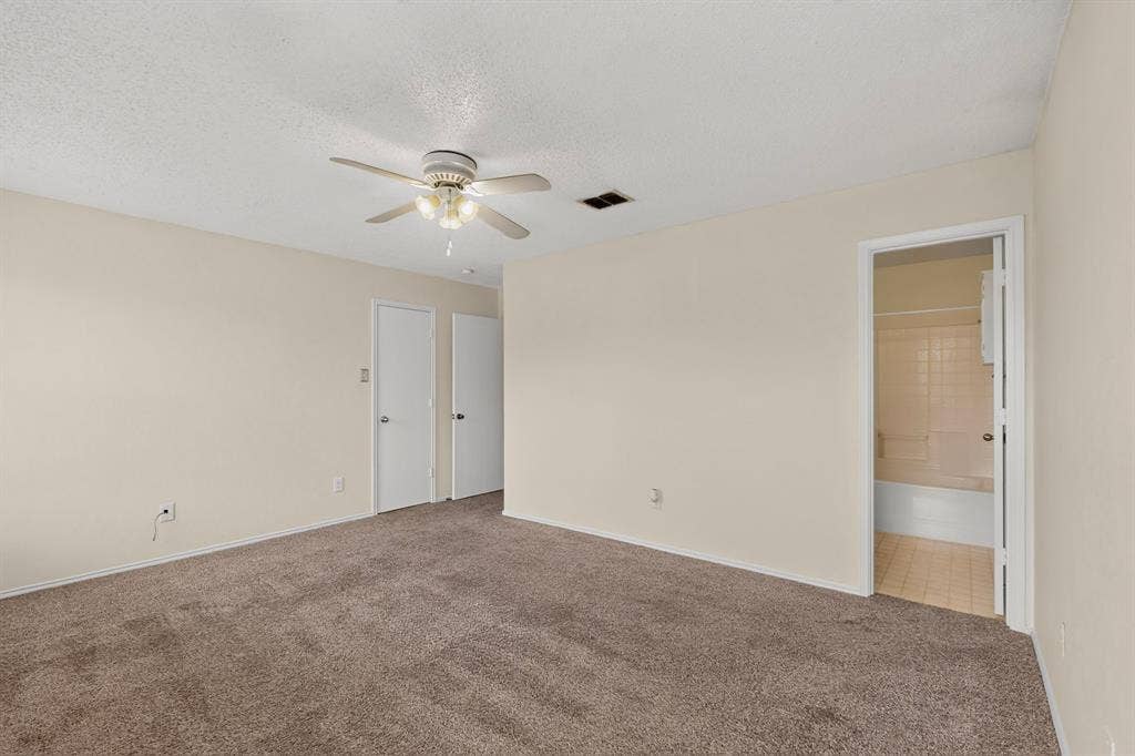3107 Westview Drive, McKinney, TX 75070 Neutral-toned interior space featuring carpeting, a ceiling fan with integrated lighting, two interior doors, and a doorway opening into a tiled bathroom