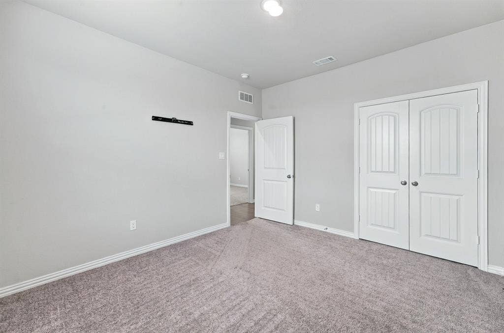 Interior room featuring neutral-toned carpeting, double-panel closet doors, and a single-panel interior door