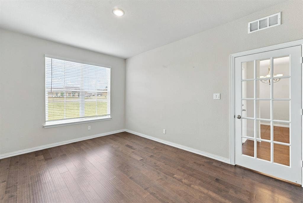 Wood-finish flooring, recessed lighting, neutral wall paint, multi-pane window with blinds, and white French door