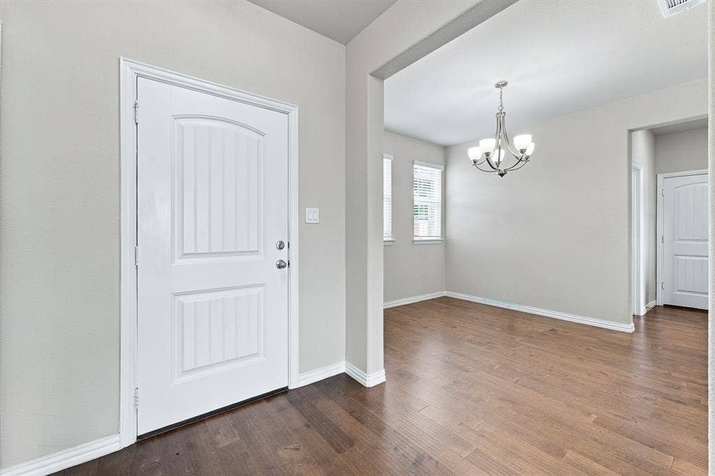 Entryway featuring wood-finish flooring, a multi-panel door with metallic hardware, and a multi-light chandelier