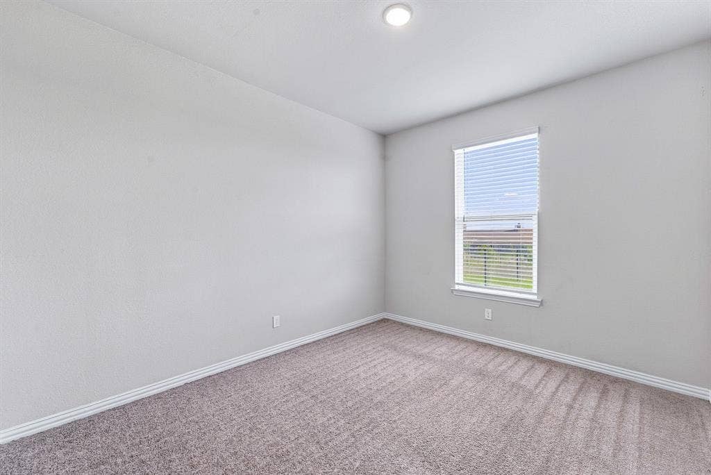 Neutral-toned interior space featuring light-colored wall texturing, wall-to-wall carpeting, and a window with horizontal blinds