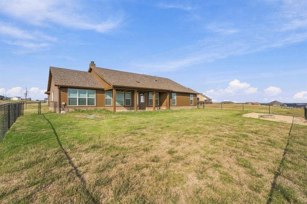 Exterior featuring horizontal siding, a covered rear porch with wood-finish columns, a fenced backyard, and a gravel fire pit area