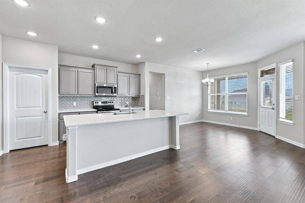 Kitchen featuring light-tone cabinetry, stone-finish countertops, herringbone-pattern tile backsplash, wood-finish flooring, and recessed lighting